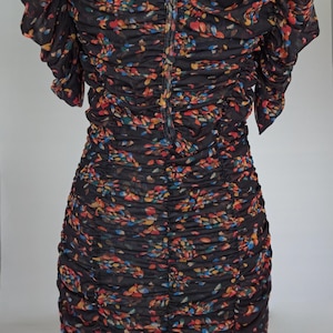May include: A black dress with a floral pattern in red, yellow, and blue. The dress has a ruched design and short sleeves. The back of the dress has a keyhole opening and a zipper closure.