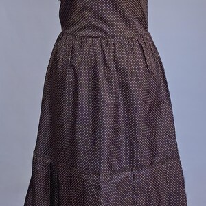 May include: A dark brown, knee-length dress with a strapless design and a pattern of small, light-coloured dots. The dress has a fitted bodice, a gathered waist, and a tiered skirt.