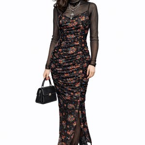 May include: A black floral print dress with a high slit, layered over a sheer black long-sleeve top. The dress is paired with black lace-up boots and a small black handbag. A silver cross necklace is visible.