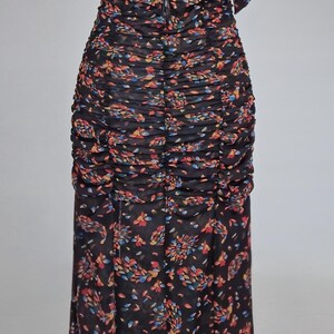 May include: Black floral print dress with a keyhole back and ruched detailing. The dress features a fitted bodice and a flowing skirt. The fabric has a semi-sheer quality, and the floral pattern includes red, blue, and yellow accents.