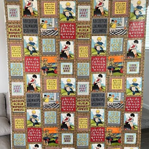 May include: A fabric panel with a repeating pattern of educational motifs. The design includes children reading, numbers, the alphabet, and a checkerboard floor, all within a grid of rectangular frames. The color scheme is mainly tan, red, and blue.