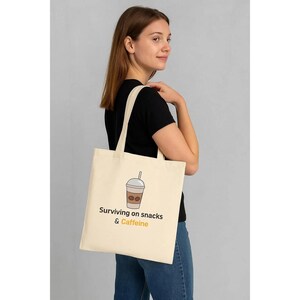 Bolsa de tela divertida para mamás: ¡Sobreviviendo con snacks y cafeína! Bolsa de algodón reutilizable para mamás agotadas y porta snacks. Disponible en varios colores.