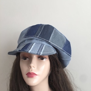 May include: A blue denim newsboy cap with a patchwork design. The cap is made of different shades of blue denim and has a slightly rounded crown.
