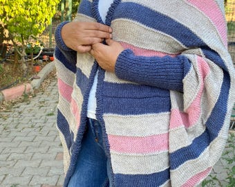 May include: A striped knitted cardigan in blue, pink, and beige. The open-front sweater has long sleeves and a relaxed fit. The cardigan is a cosy and stylish layering piece.