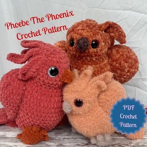 Pode incluir: Três pássaros fénix de croché em tons de vermelho, laranja e pêssego. Os pássaros têm olhos grandes e pretos e são feitos com um fio macio e texturizado. O texto "Phoebe The Phoenix Crochet Pattern" está no topo. Um distintivo azul diz "PDF Crochet Pattern".