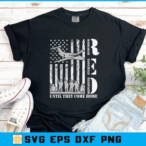 May include: Black t-shirt with a patriotic design featuring an American flag, a jet, and silhouettes of soldiers. The text reads "RED, Remember Everyone Deployed, Until They Come Home."