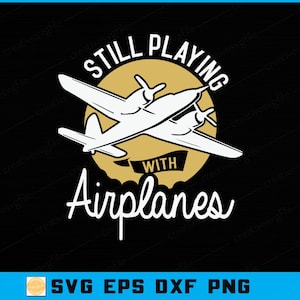 May include: A black graphic design features a white airplane illustration with the text "STILL PLAYING WITH Airplanes" in a vintage style. The airplane is set against a gold circle. The bottom of the image includes "SVG EPS DXF PNG".