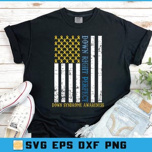 May include: Black t-shirt with a distressed American flag design featuring yellow ribbons, the text "Down Right Perfect," and "Down Syndrome Awareness." White sneakers and blue jeans are visible.