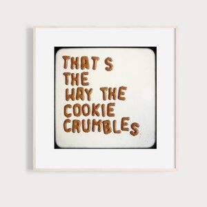 May include: A white background with the phrase "THAT'S THE WAY THE COOKIE CRUMBLES" spelled out in brown cookie dough.