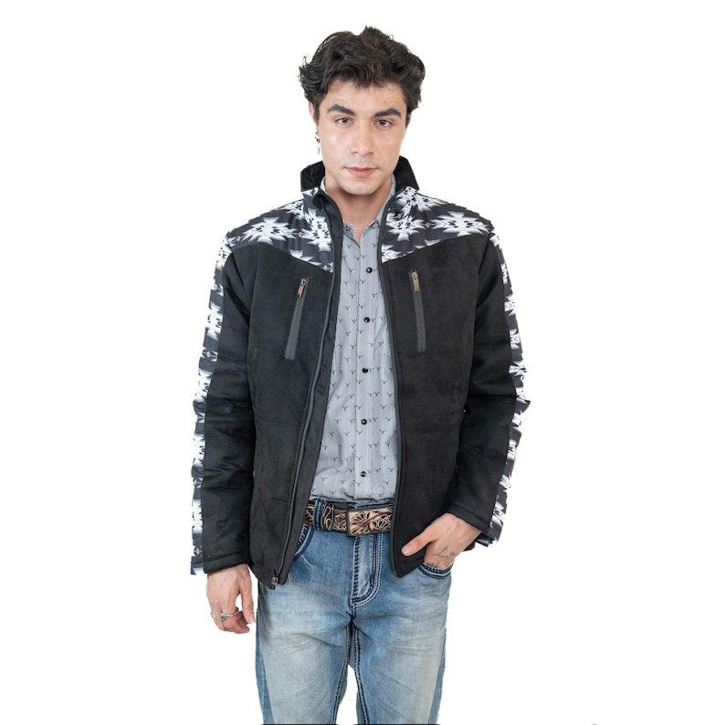 May include: Black suede jacket with white and black geometric pattern on the shoulders and sleeves. The jacket has a zipper closure and two front pockets. The person is wearing a gray button-down shirt and blue jeans.