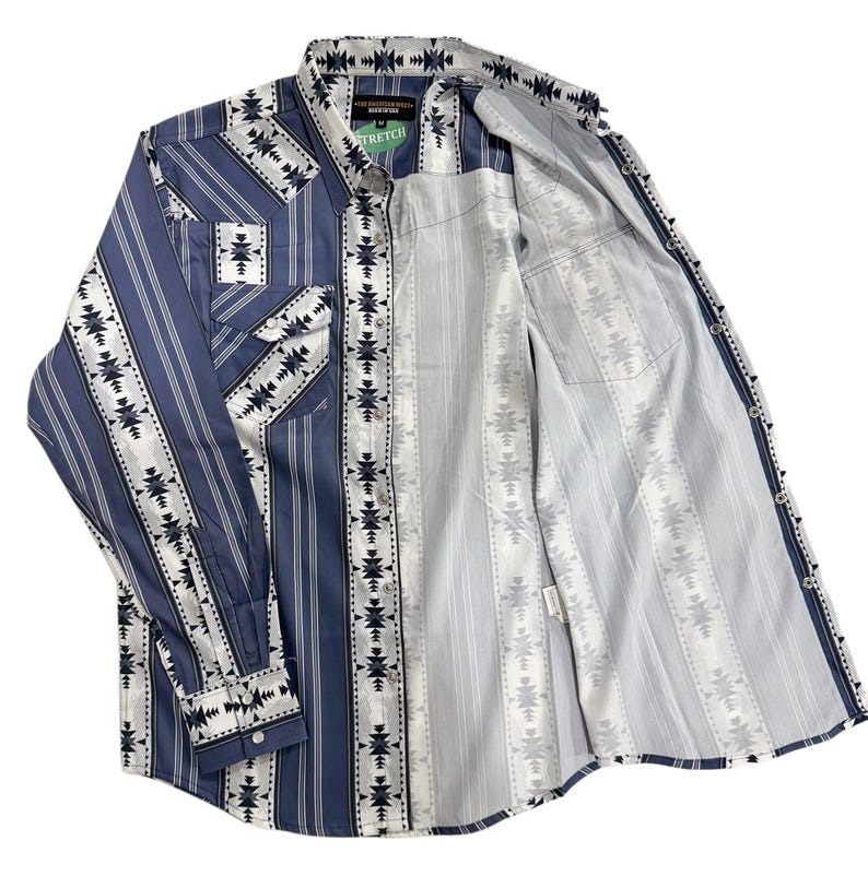 May include: A long-sleeved button-down shirt with a blue and white geometric pattern. The shirt features a striped design on the front and sleeves, with a contrasting pattern on the yoke and pockets. The shirt is open, revealing the inside lining.