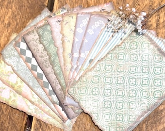 May include: A collection of vintage-style paper ephemera with various patterns and colors, including floral, geometric, and striped designs. The edges are scalloped and distressed, with a dried flower accent.