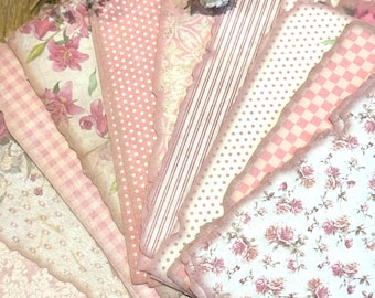 May include: A collection of pink and white patterned paper sheets with scalloped edges. The designs include floral, polka dot, striped, and checkered patterns. Dried white flowers are placed on top of the paper sheets.