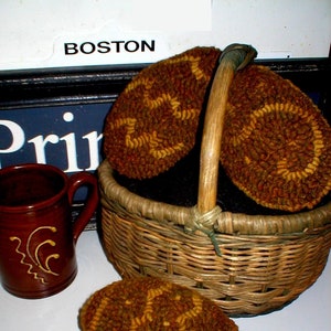 May include: Three brown and gold knitted pot holders in a wicker basket with the word "BOSTON" on a white sign above the basket.