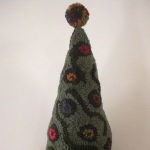 May include: A green felt Christmas tree ornament with a multi-colored pom-pom on top. The tree is decorated with colorful felt flowers.