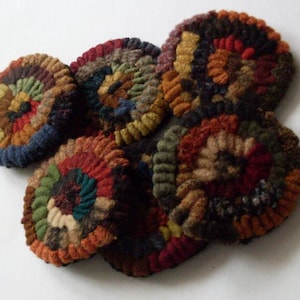 May include: A set of six colorful wool rug hooking circles in shades of brown, red, blue, and green. The circles are hand-stitched and feature a spiral pattern.