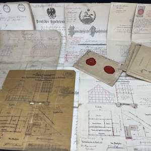 Könnte beinhalten: Eine Sammlung antiker deutscher Dokumente, darunter architektonische Grundrisse mit handgezeichneten Skizzen, offizielle Urkunden mit schwarzem Tintendruck, gedruckte Formulare und ein gefalteter Papierumschlag mit zwei runden roten Wachssiegeln.