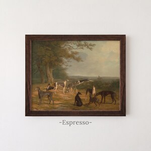 May include: A framed landscape painting featuring a group of greyhounds in a field with trees under a cloudy sky. The dogs are depicted in various poses, including standing, sitting, and lying down. The frame is dark brown wood. The text -Espresso- is below.