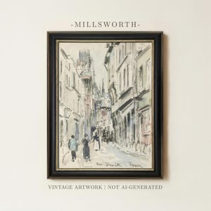 May include: A framed watercolor painting depicting a street scene in Rouen, France, titled Rue Damiette. The artwork features tall buildings, figures walking along the cobblestone path, and a church spire in the distance, all enclosed in a black frame.