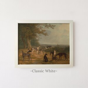 May include: A framed landscape painting featuring a group of greyhounds in a field with trees under a cloudy sky. The artwork is enclosed in a classic white frame. Below the frame, the text -Classic White- is printed in a dark grey font.