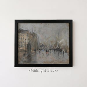 May include: A framed painting in a black frame depicting a rainy harbor scene with buildings, ships, and figures walking along a wet street. The artwork features muted gray, brown, and tan tones with small pops of red and blue on the figures.