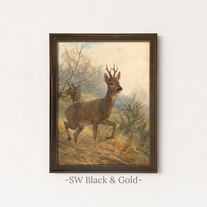 May include: A framed wall art print featuring an oil painting of a brown roe deer with antlers standing in a grassy field, with a second smaller deer visible in the background near bare trees, all enclosed in a dark brown textured frame.