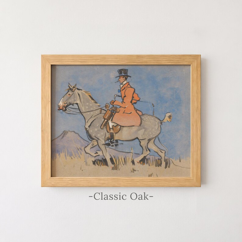 May include: A framed print in a light-colored wooden frame featuring an illustration of a person in an orange coat and top hat riding a grey horse. The scene includes a blue sky and a tan landscape. The text -Classic Oak- is printed below the frame.