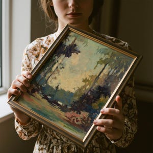 May include: A framed landscape painting featuring loose, expressive brushstrokes in shades of muted green, deep blue, and soft cream. The artwork is encased in a simple, dark metallic frame with a subtle sheen, showcasing a signature at the bottom.