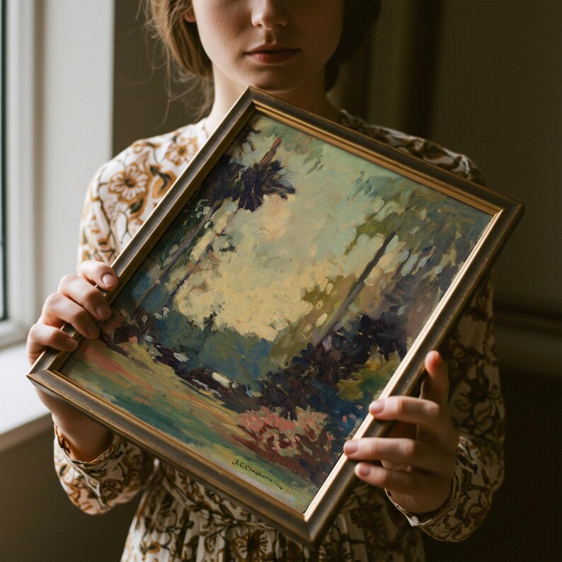 May include: A framed landscape painting featuring loose, expressive brushstrokes in shades of muted green, deep blue, and soft cream. The artwork is encased in a simple, dark metallic frame with a subtle sheen, showcasing a signature at the bottom.