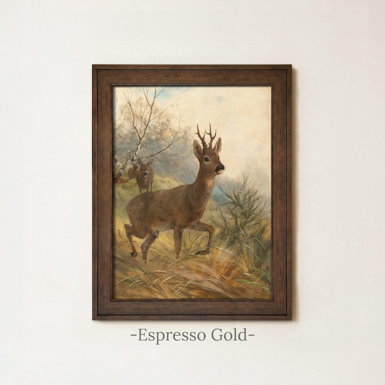 May include: A framed wall art print featuring a painting of a brown deer standing in a grassy field with a smaller deer in the background. The artwork is enclosed in a dark brown wooden frame. Below the frame, the text reads Espresso Gold.