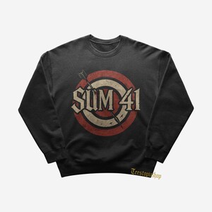 May include: Black sweatshirt featuring the band name "SUM 41" in a distressed, vintage-style design. The graphic includes a target with red and cream concentric circles, and an arrow piercing through the center. The sweatshirt has a crew neck.