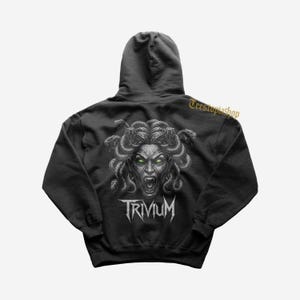 May include: Black hooded sweatshirt featuring a Medusa graphic with snakes for hair and glowing green eyes. The word "TRIVIUM" is printed in white below the graphic. The sweatshirt has a drawstring hood and a kangaroo pocket.