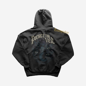May include: Black hooded sweatshirt featuring the band name "Pierce the Veil" in a gothic font across the upper back. Below the text is a dark graphic of a spectral figure with multiple eyes. The sweatshirt has a drawstring hood.