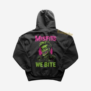 May include: Black hoodie with a green and pink zombie graphic, the word "Misfits" above and "We Bite" below. The design has a punk rock theme.