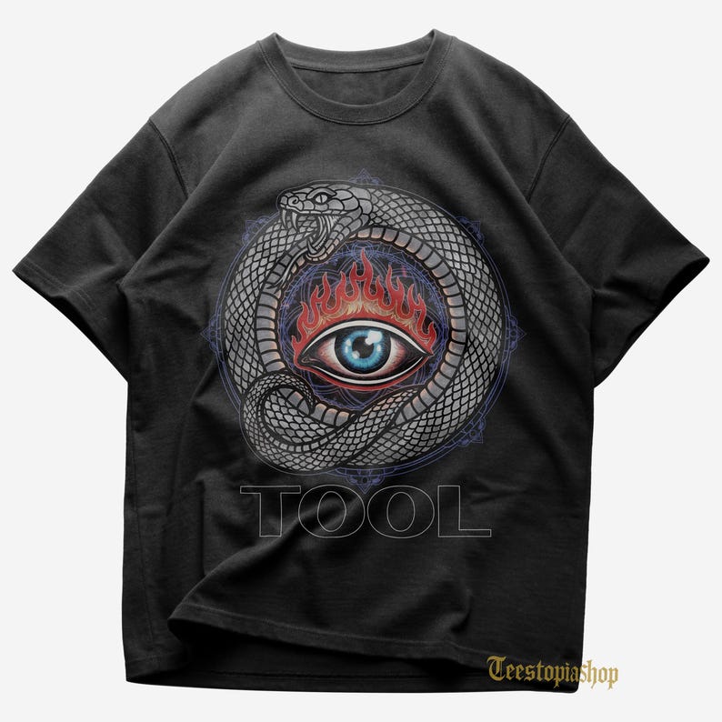 Puede incluir: Camiseta negra con un gr&aacute;fico detallado de una serpiente enroscada alrededor de un ojo en llamas. El ojo es azul con llamas rojas. La palabra "TOOL" est&aacute; impresa en blanco debajo.