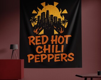May include: Black wall tapestry featuring a stylized orange sun, palm trees, and a cityscape silhouette. The words "RED HOT CHILI PEPPERS" are printed in orange, below the graphic. The tapestry is a decorative item.