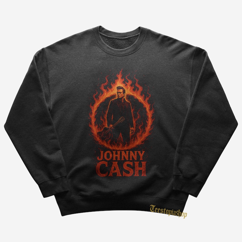 May include: Dark gray sweatshirt featuring a graphic of Johnny Cash inside a ring of flames. The image shows Cash holding a guitar, with the name "JOHNNY CASH" in red block letters below. The sweatshirt is a crew neck style.