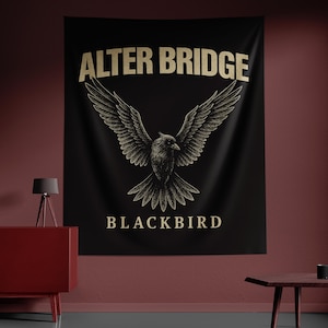 May include: Black tapestry featuring the words "ALTER BRIDGE" above a detailed illustration of a bird with outstretched wings. Below the bird, the word "BLACKBIRD" is displayed in a matching font. The design is in gold against a black background.