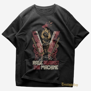 Pode incluir: Camiseta preta com um design gráfico que apresenta uma mão segurando uma tocha, chamas e o texto "RAGE AGAINST THE MACHINE". O design incorpora um megafone, engrenagens e arame farpado. A camiseta tem gola redonda.