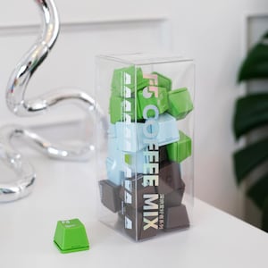 Pu&ograve; includere: Una scatola trasparente piena di cubetti di miscela di caff&egrave; verdi, blu e marroni. Il testo "F5 COFFEE MIX" &egrave; stampato verticalmente sulla scatola. Un singolo cubo verde &egrave; su una superficie bianca.