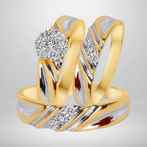 May include: Three-piece ring set featuring a gold band with a silver inlay design. One ring has a cluster of small, round, clear stones. The other two rings have a series of clear stones. The rings are set against a light gray background.