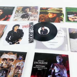 Op de afbeelding: Een verzameling Michael Jackson albumhoezen en een vinylplaat. De albumhoezen tonen verschillende afbeeldingen van de artiest, met titels als "Bad", "History" en "Invincible". De vinylplaat is zwart met een centraal label met een portret van Michael Jackson.