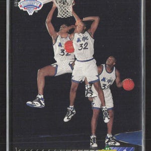 May include: A basketball trading card featuring Shaquille O'Neal in a white and blue Orlando Magic uniform. The card shows multiple images of O'Neal in action, with the NBA Draft logo at the top. The Upper Deck logo is visible.