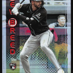 May include: A Topps baseball trading card featuring Jordan Lawlar in a black jersey and light gray pants, holding a bat. The card displays the text NEW BREED vertically in red circles, the Topps logo, an RC rookie symbol, and the name Jordan Lawlar.