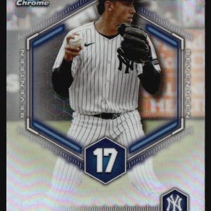 May include: A Bowman Chrome Top 100 baseball card featuring George Lombard Jr. in a white pinstriped New York Yankees uniform. The card displays a hexagonal frame, the number 17, the Yankees logo, and a holographic finish with geometric patterns.