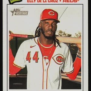 May include: A 2025 Topps Heritage baseball card featuring Elly De La Cruz of the Reds. The card displays the text RECORD BREAKER, the player's name, and a description of his MLB history. The player wears a white jersey with the number 44.