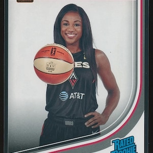 May include: A basketball trading card featuring Jackie Young of the Las Vegas Aces. The card has a red and white border with the Donruss logo. Jackie Young is wearing a black jersey with the AT&T logo and holding a basketball. The card is labeled "Rated Rookie."