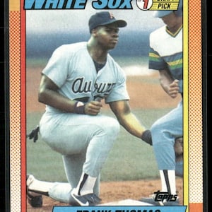 May include: A baseball card featuring Frank Thomas of the White Sox. The card has a blue, red, and white border. Thomas is kneeling in a light blue uniform with the word "Auburn" on the jersey. The card also includes the text "White Sox" and "Frank Thomas".