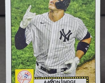 May include: A Topps baseball card featuring Aaron Judge of the New York Yankees. Judge is wearing the team's pinstripe uniform and a black helmet. The card has a white border with the Topps logo at the top and Judge's name and signature.