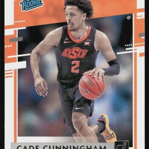 May include: A basketball trading card featuring Cade Cunningham in an Oklahoma State Cowboys uniform. The card has a "Rated Rookie" logo and the player's name. The image shows Cunningham dribbling a basketball.